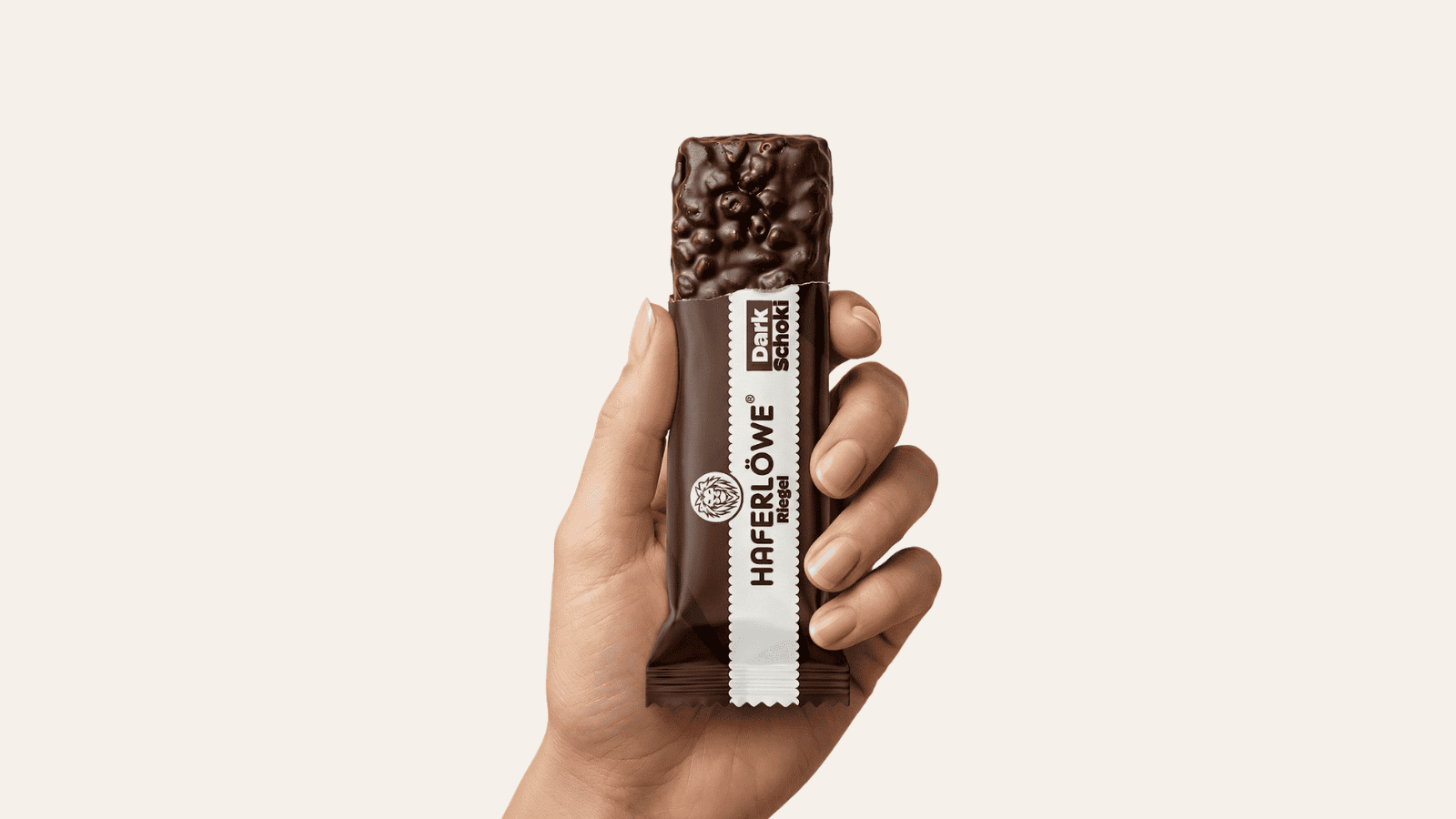 Hand hält den HAFERLÖWE DIA2®-Riegel in der Sorte Dark Schoki – dunkler Schokoüberzug mit knusprigen Crispies